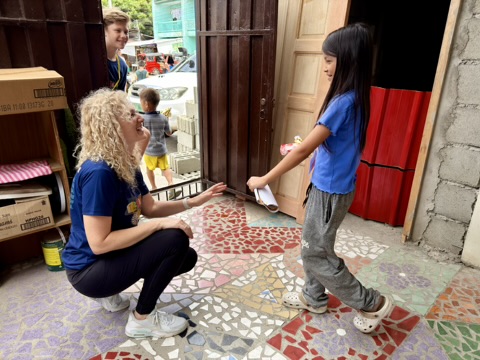 A volunteer welcoming a child at the Oasis Family Center door